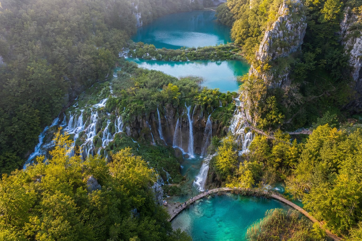 Türkisblauer See durch Baumstämme an den Plitvicer Seen